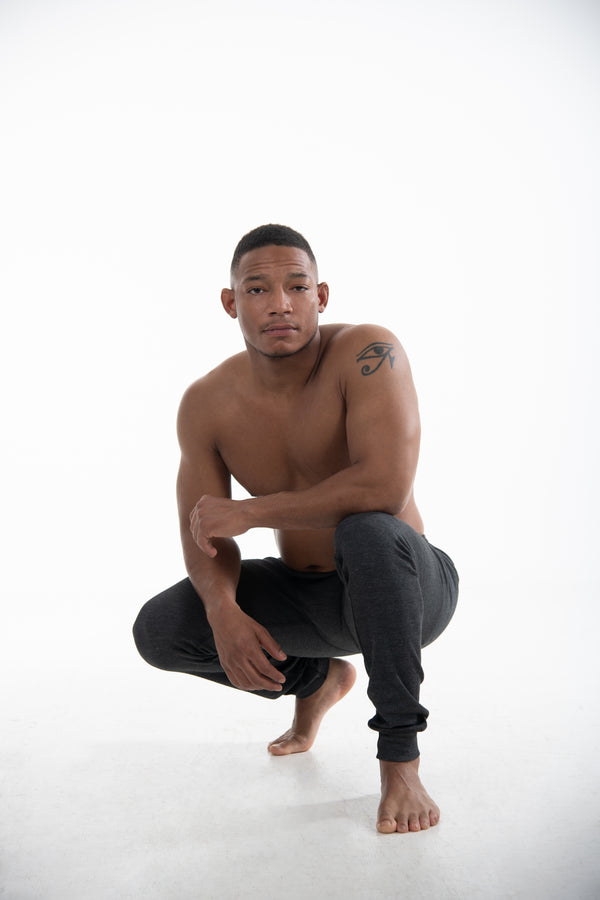 Man squatted down wearing Seraphina Safety Apparel's Men's FR Tech Cool Down Flame-Resistant base legging.  The leggings are dark grey in color and the man is bare foot. 